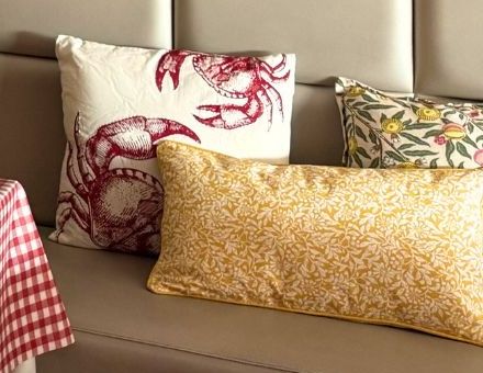 Coussins brodés de crabes rouges et coussin fleuri jaune sur la banquette.