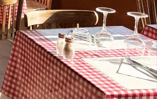 Table dressée avec nappe vichy rouge, verres à pied retournés, sel et poivre.
